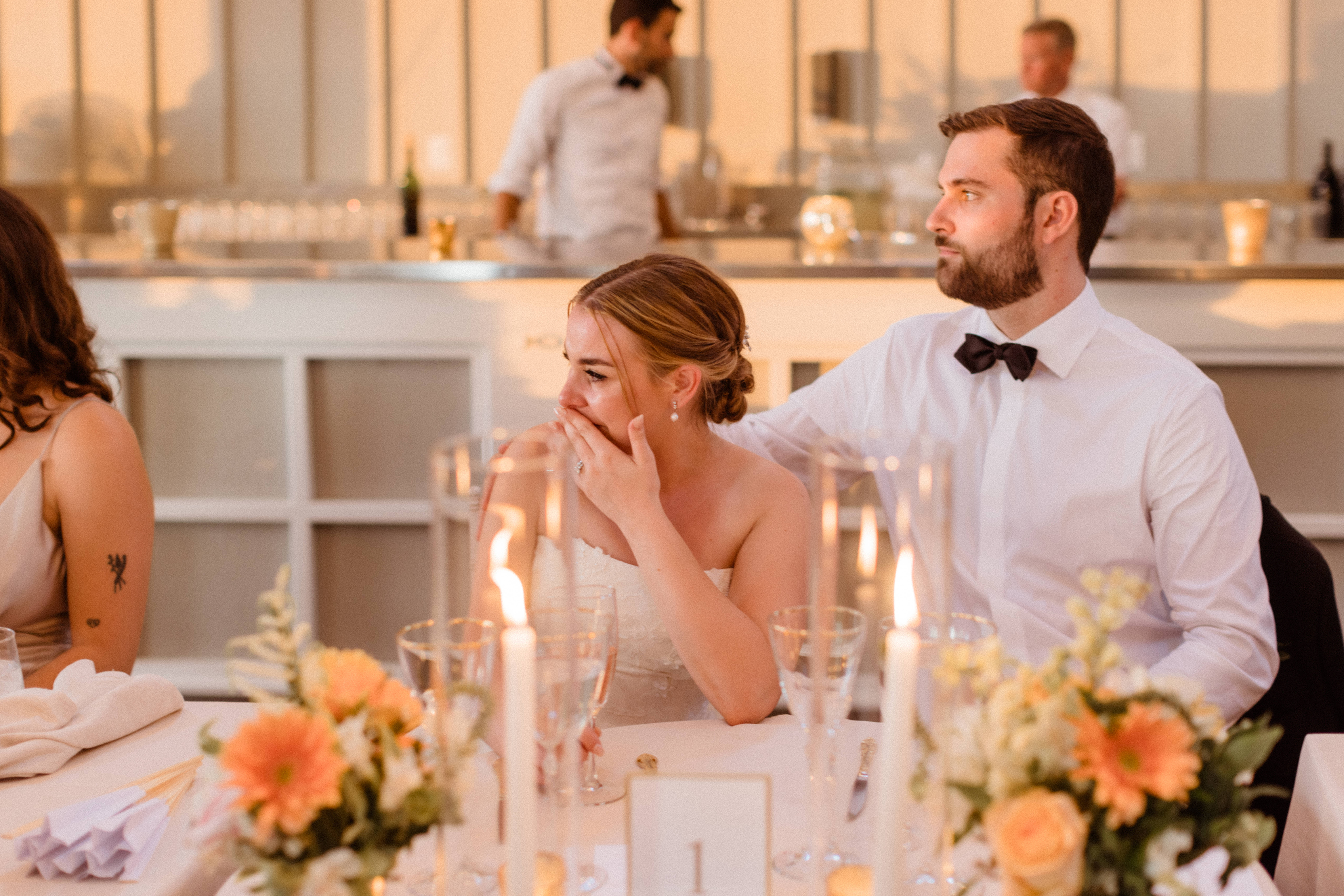 Bride and groom look on as their wedding party gives emotional toasts