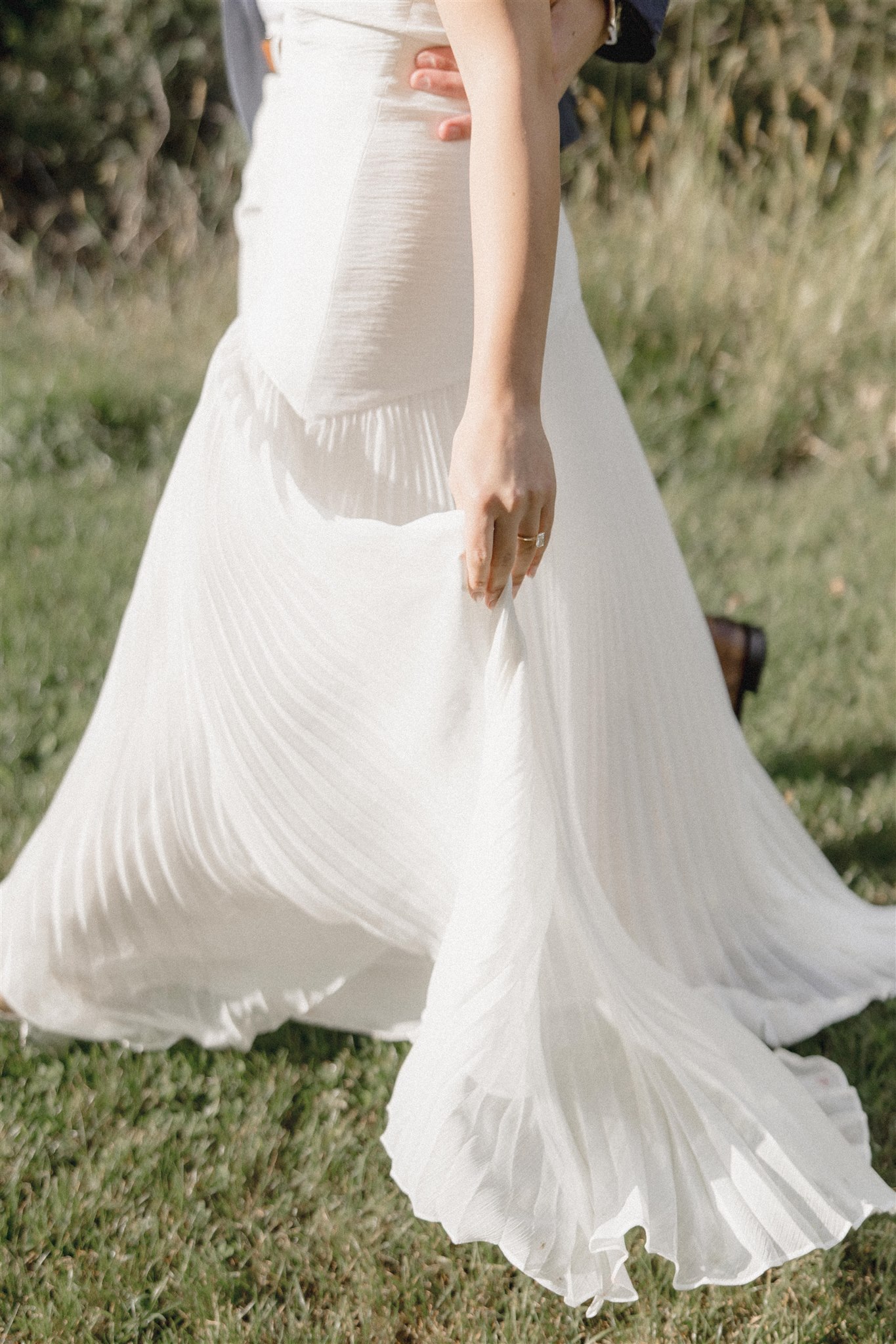 Bride showcases her dress with the striking green grass as a background