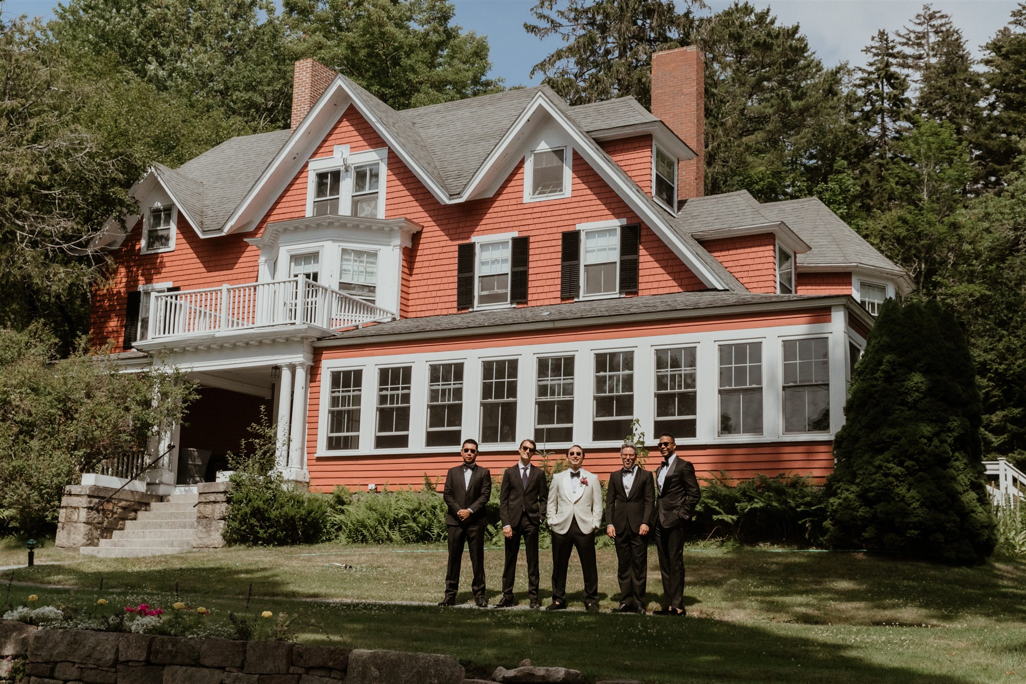 groom and groomsmen pose in front of the stunning Asticou inn