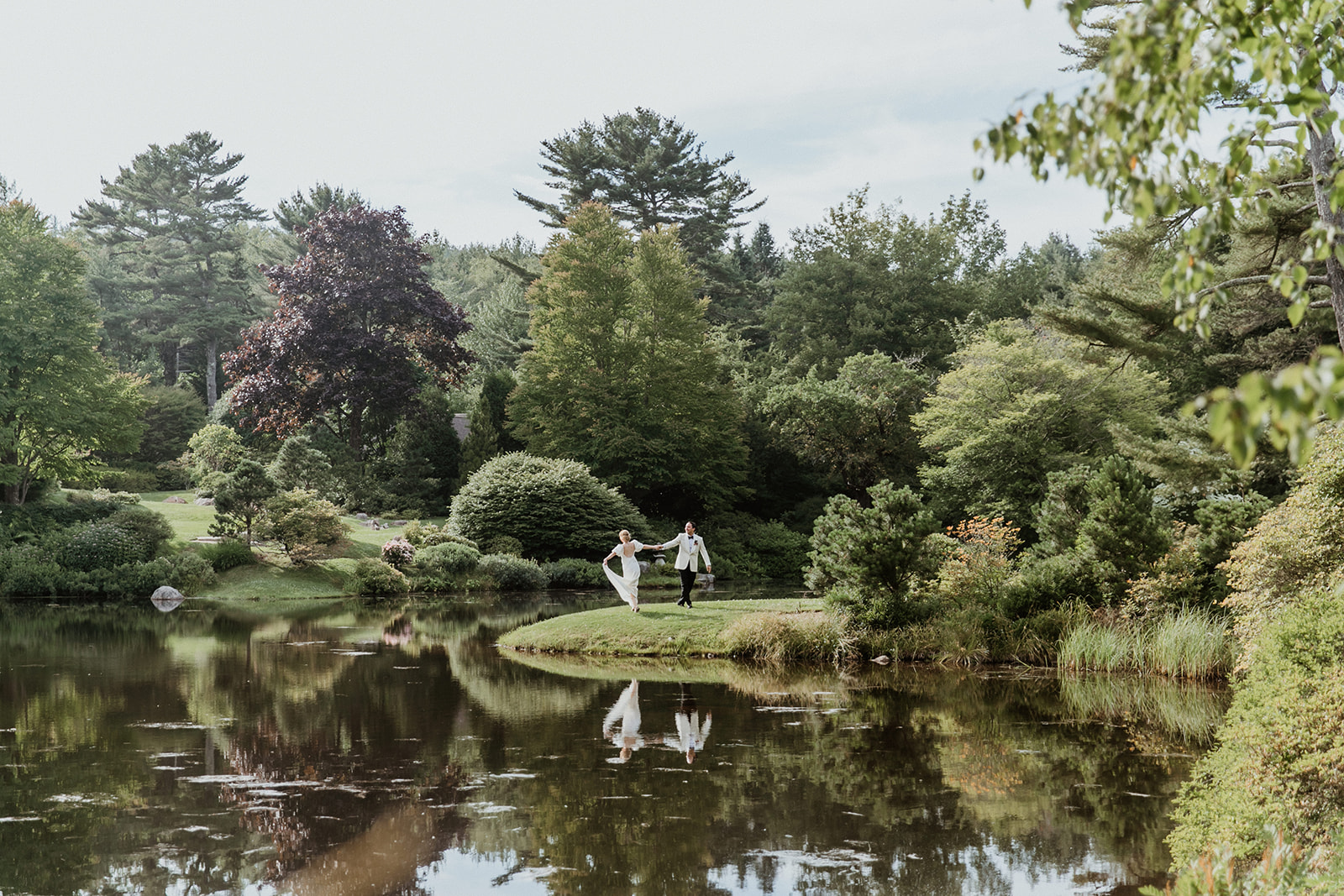 stunning bride and groom pose beside a beautiful Maine pond