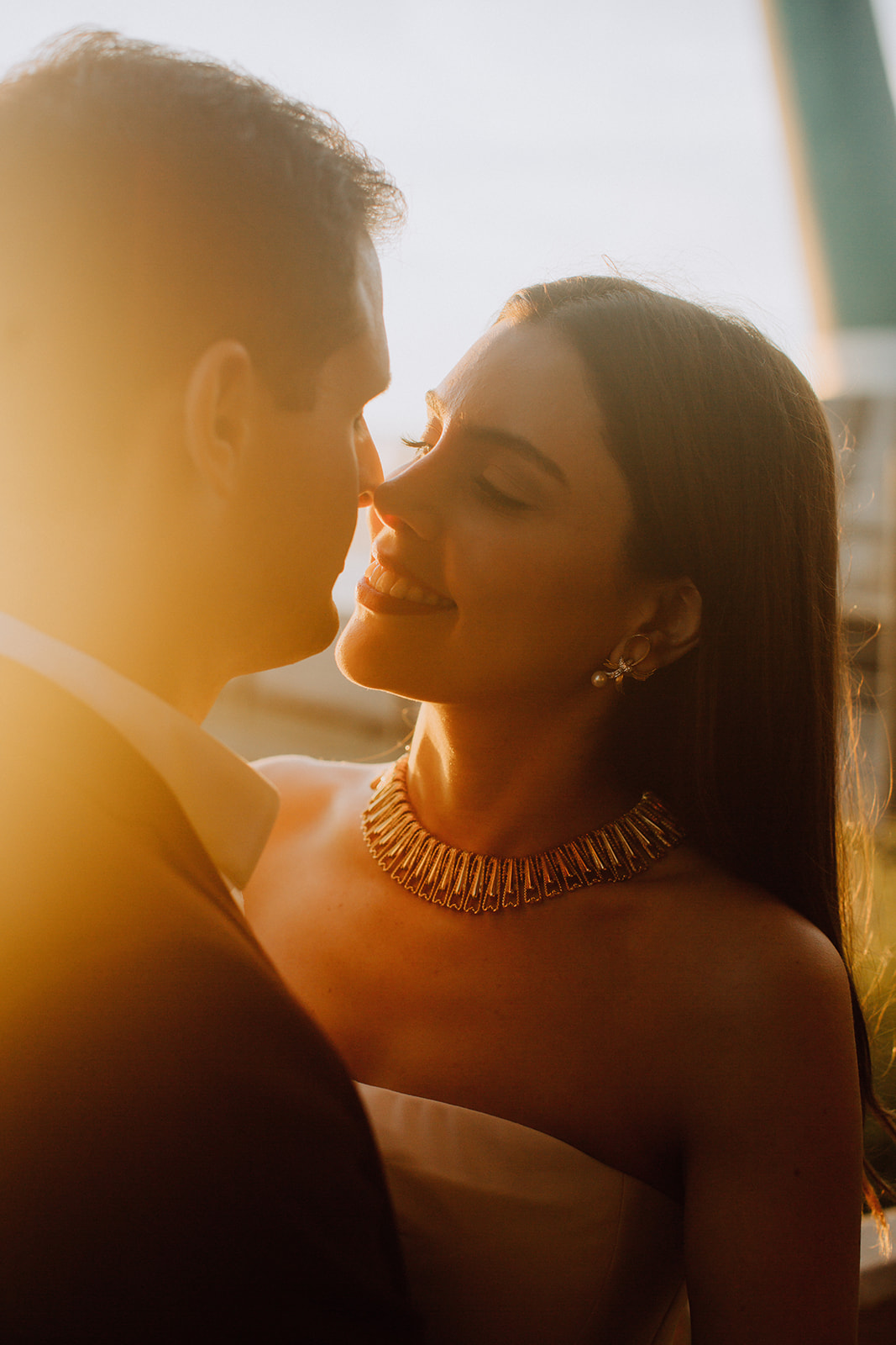 couple pose together with the beautiful sunset in the background during their dreamy wedding rehearsal photography