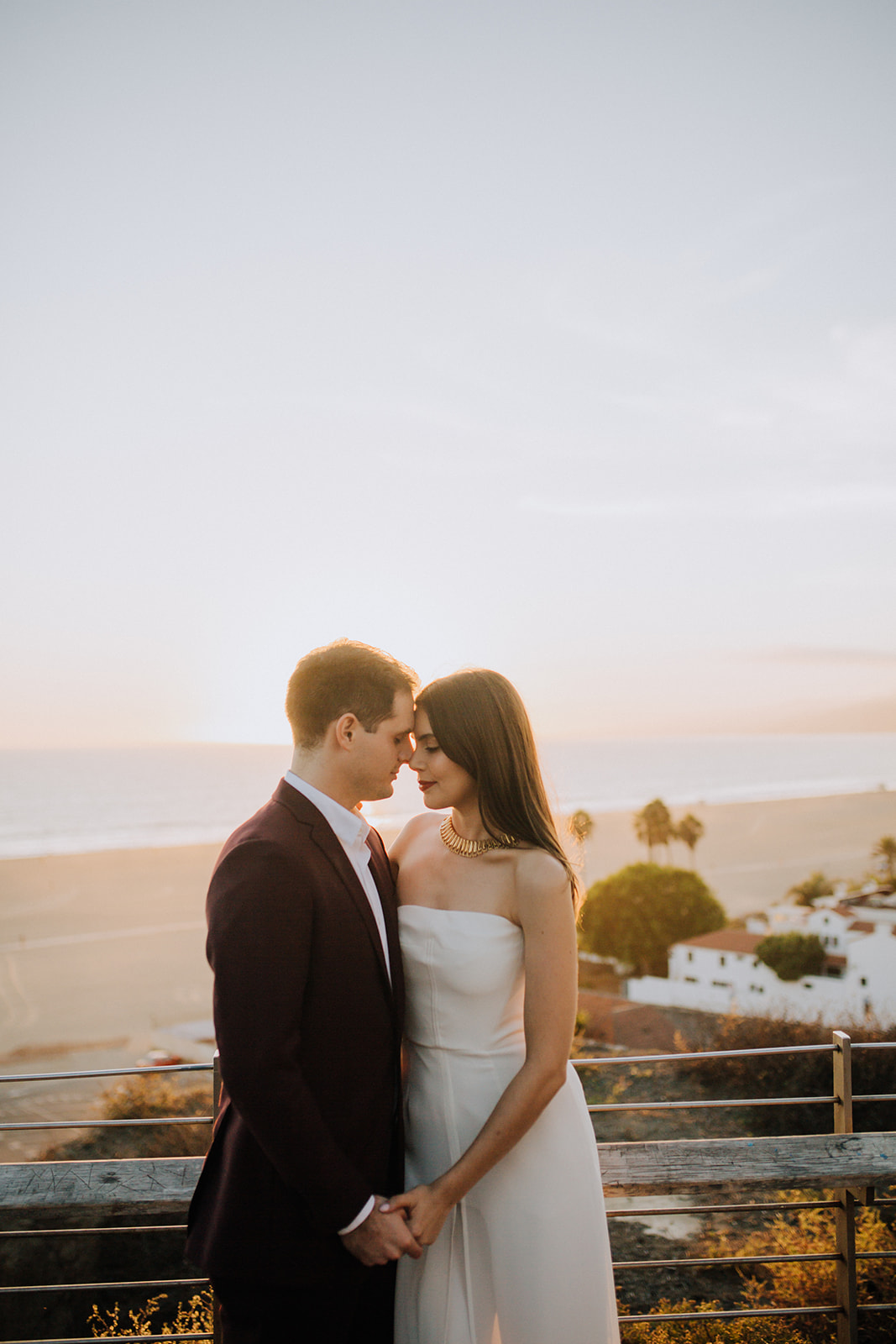 couple pose together with the beautiful beach in the background during their dreamy wedding rehearsal photography
