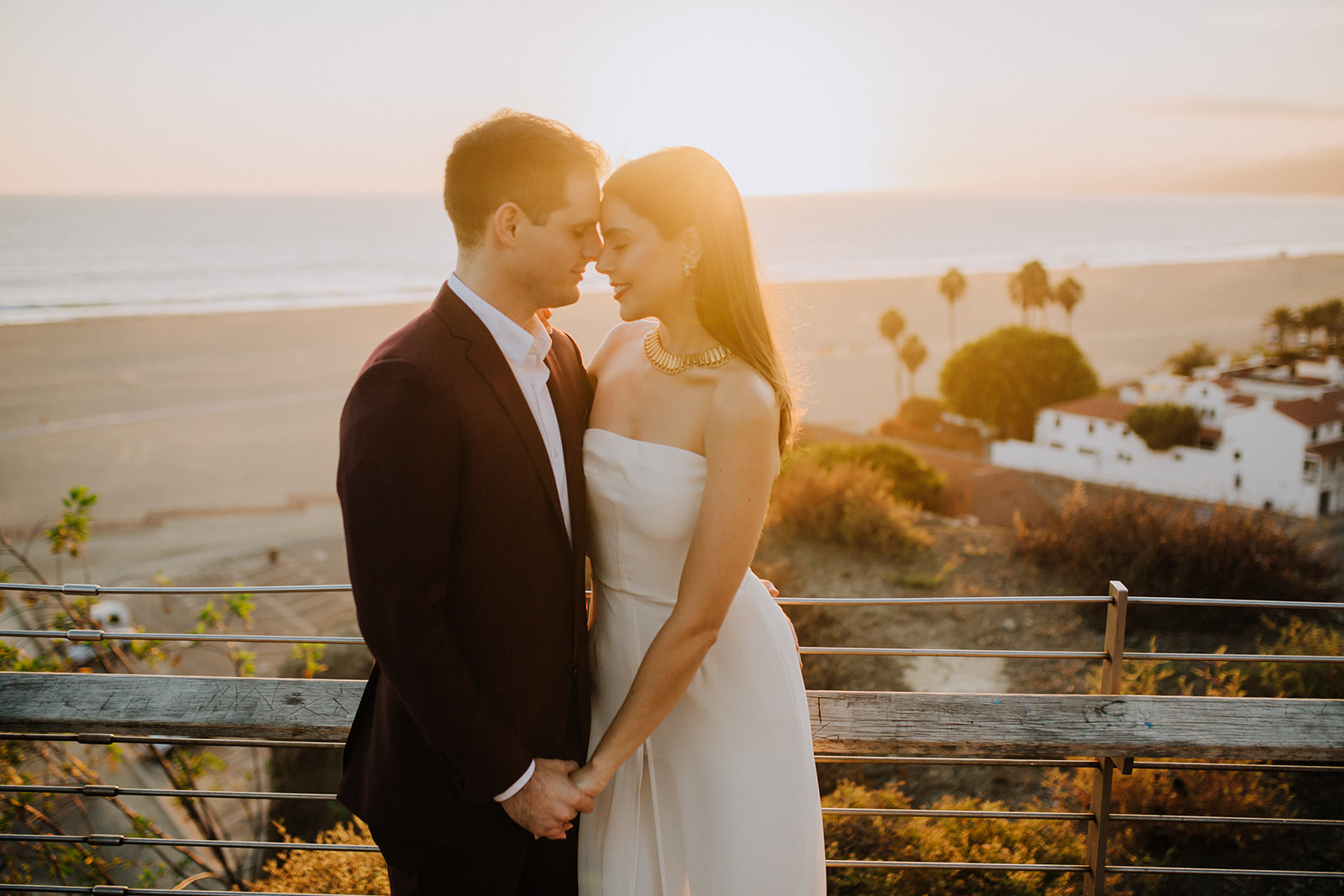 couple pose together with the beautiful beach in the background during their dreamy wedding rehearsal photography