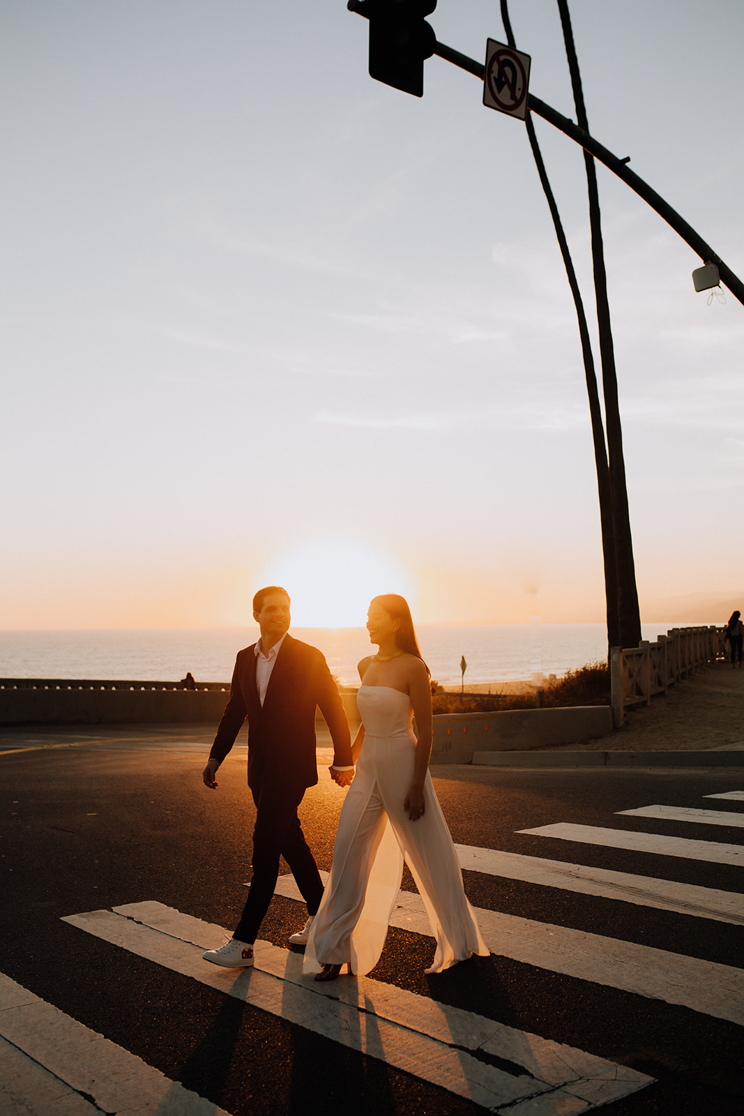 stunning couple walk together with the beautiful West Coast sunset in the background