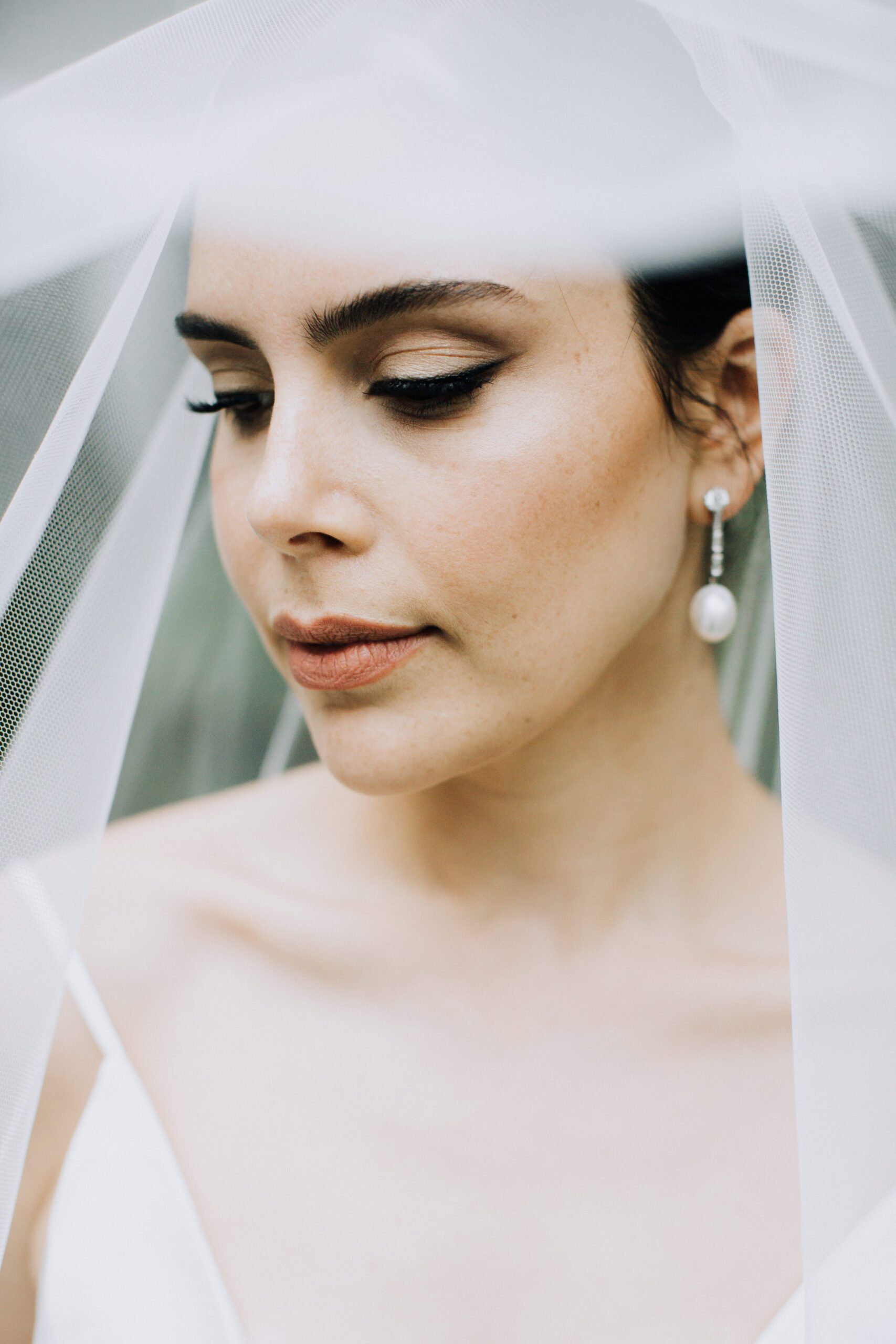 bride poses under her veil during her dreamy wedding bridal portraits