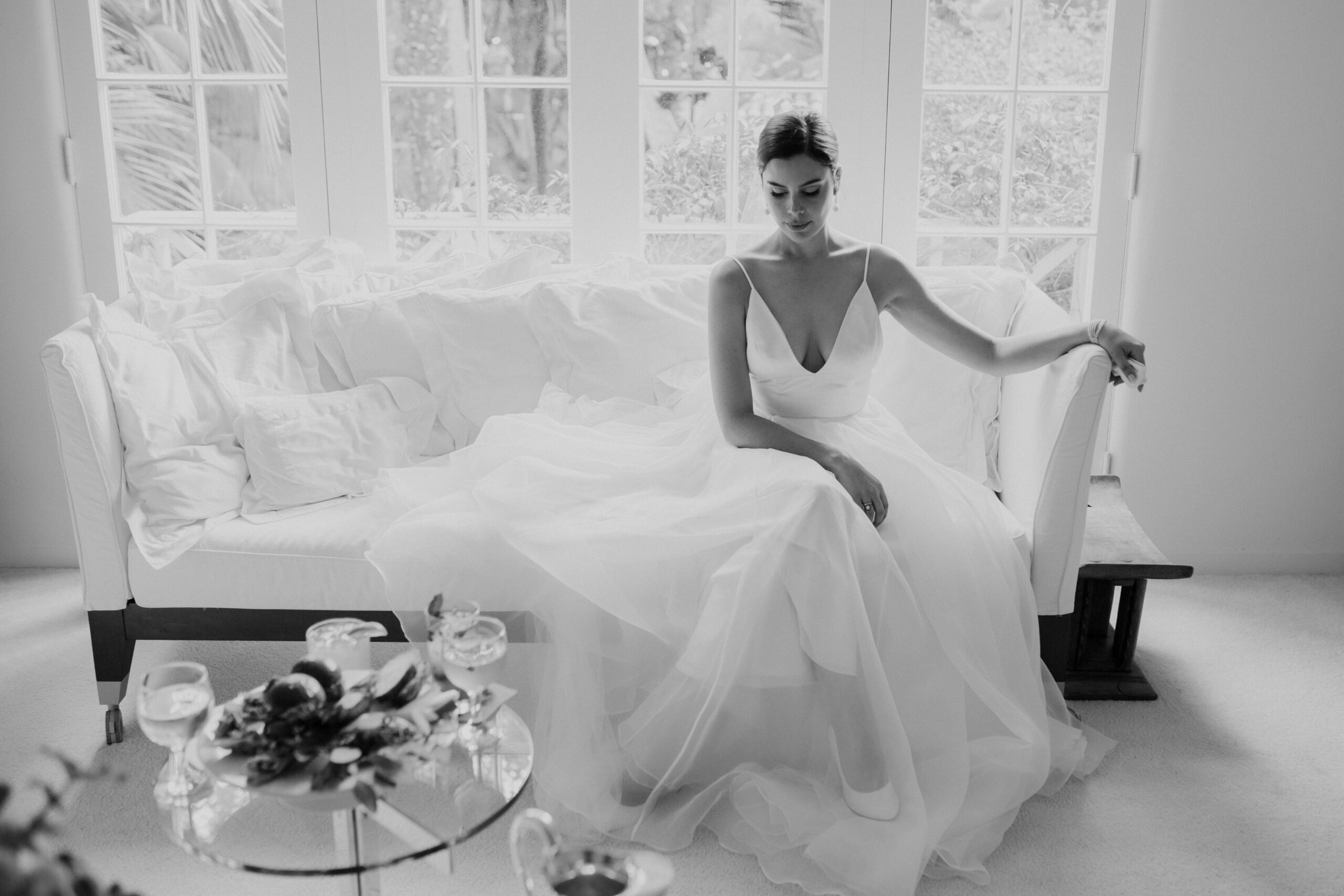 bride poses on a couch with sunlight coming through the windows