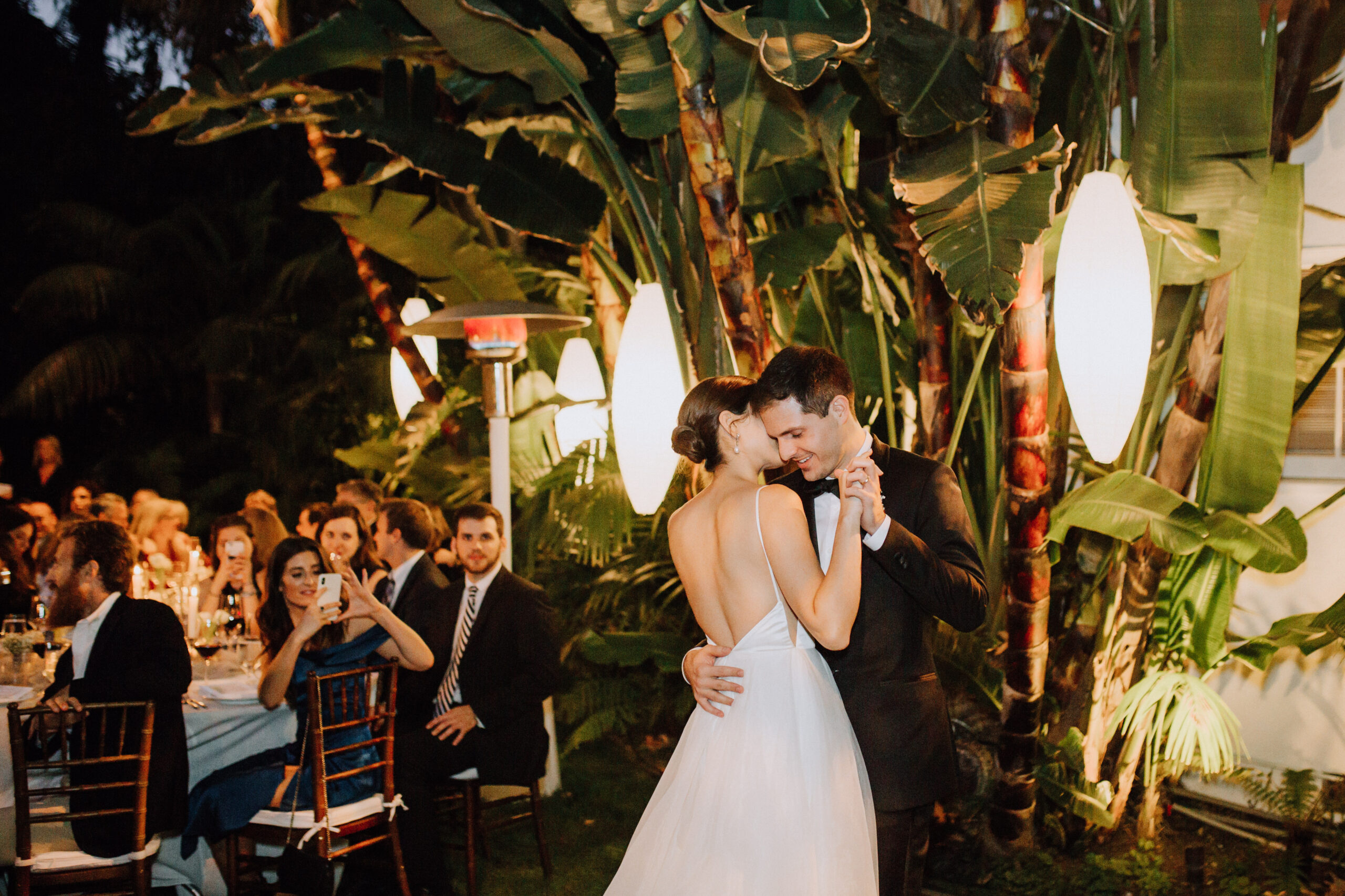 guests look on during the backyard garden wedding reception as the bride and groom share their first dance together