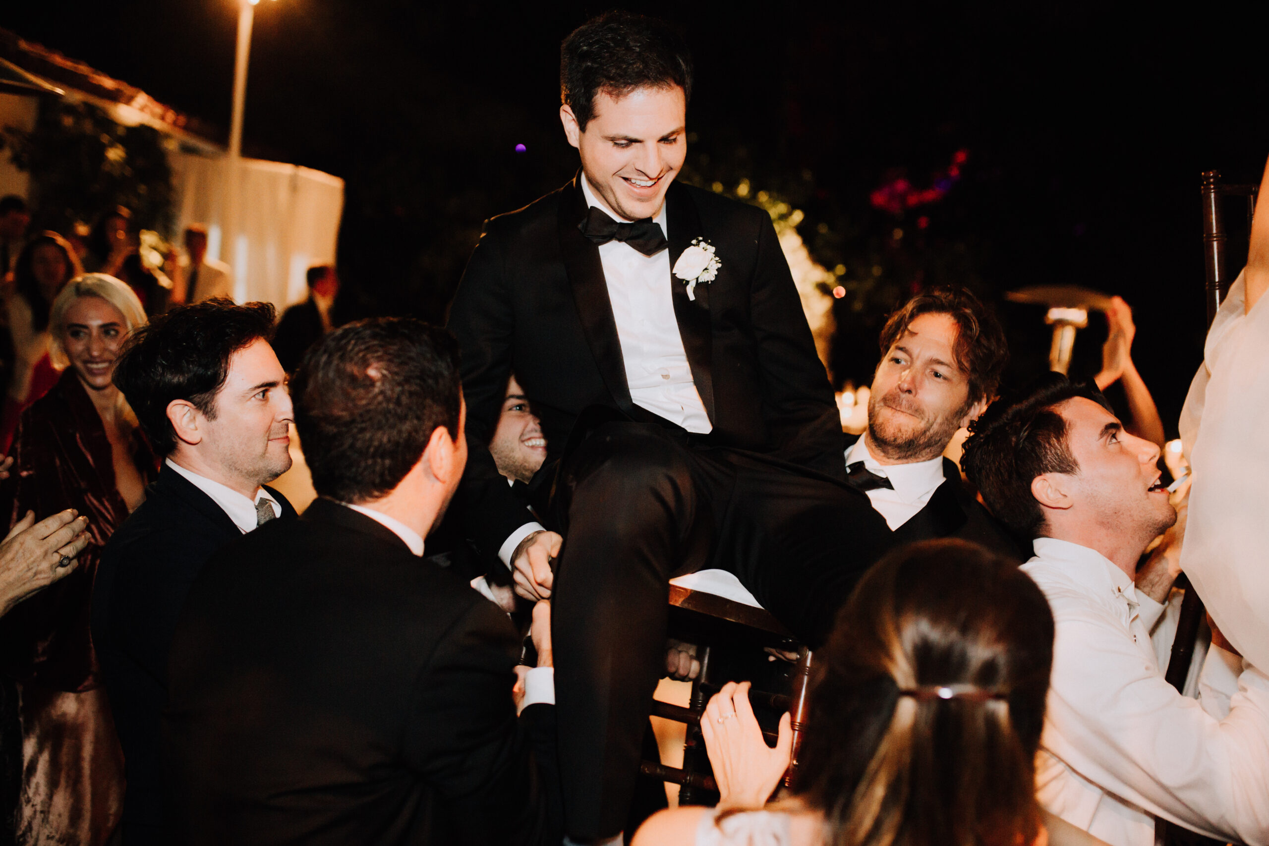 groomsmen lifts the groom in a chair during his wedding reception