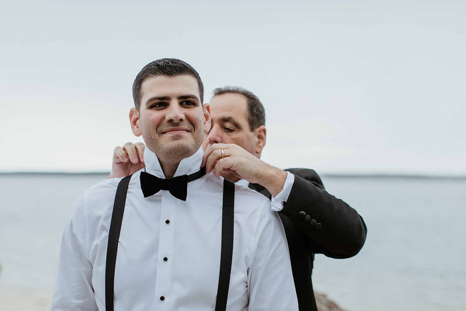 groom gets help adding his final touches before his elegant wedding day