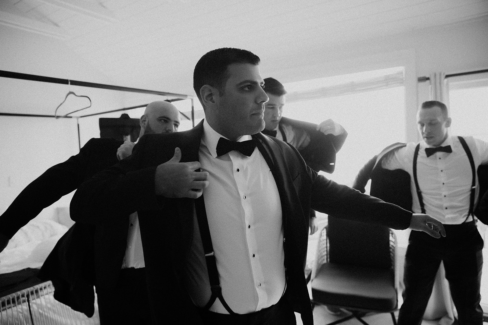 groom gets help adding his final touches before his elegant wedding day