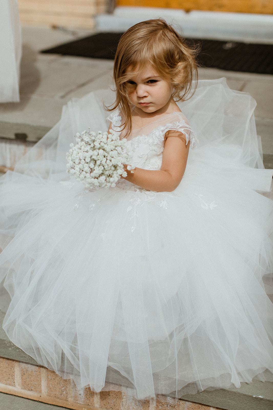 flower girl holds her small whit bouquet  