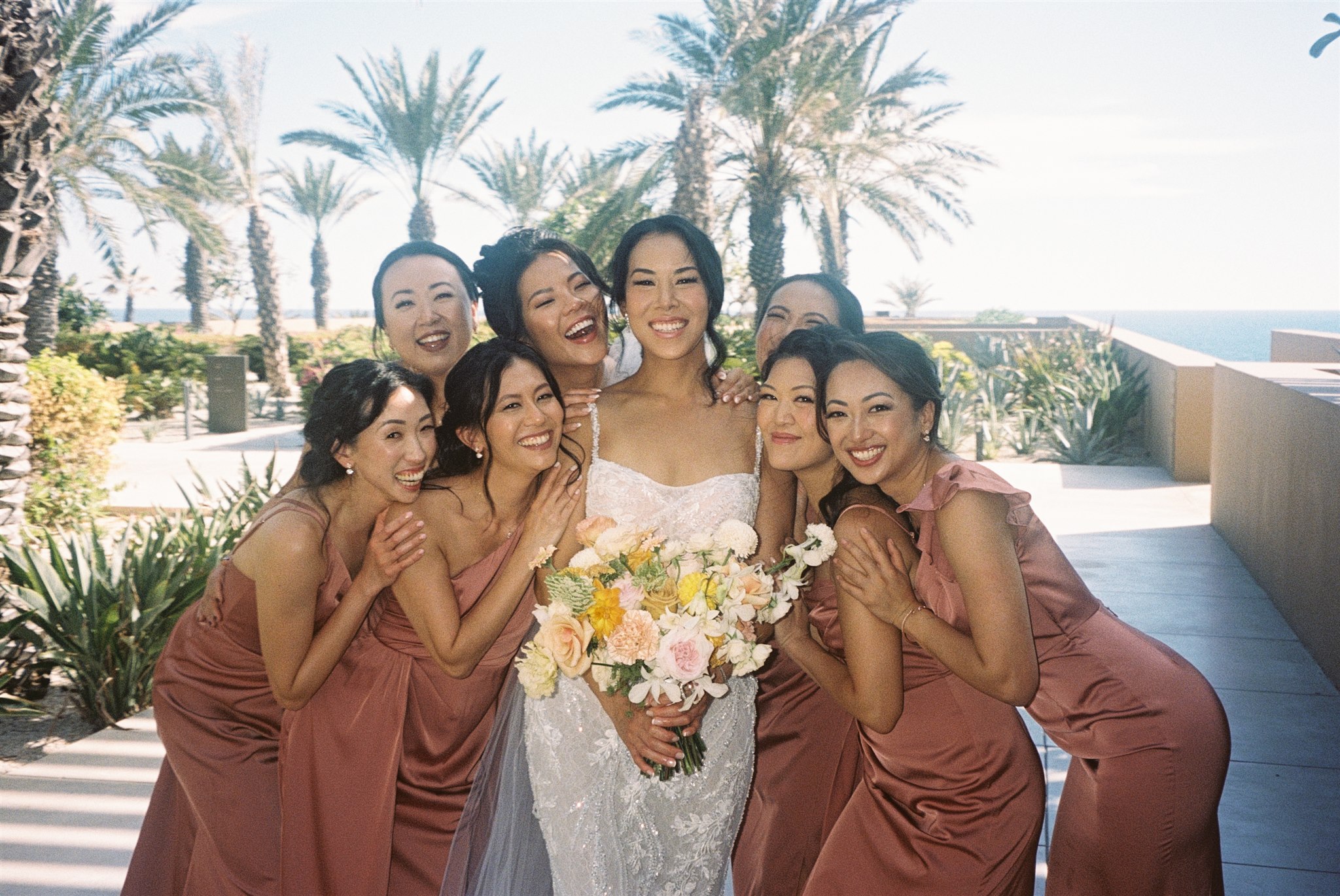 bridesmaids pose with the bride on her stunning acre baja wedding day