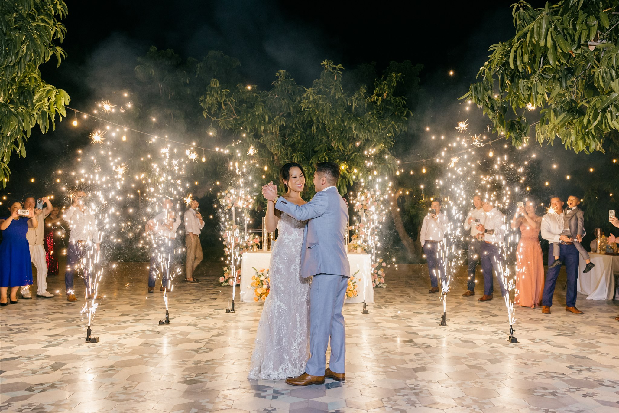 fireworks go off behind the bride and groom as they dance