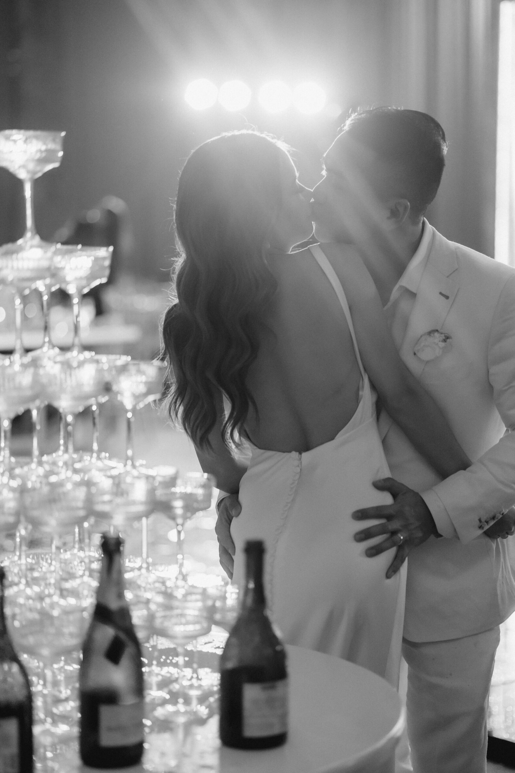 champagne tower gets filled with bride and groom kissing in the background