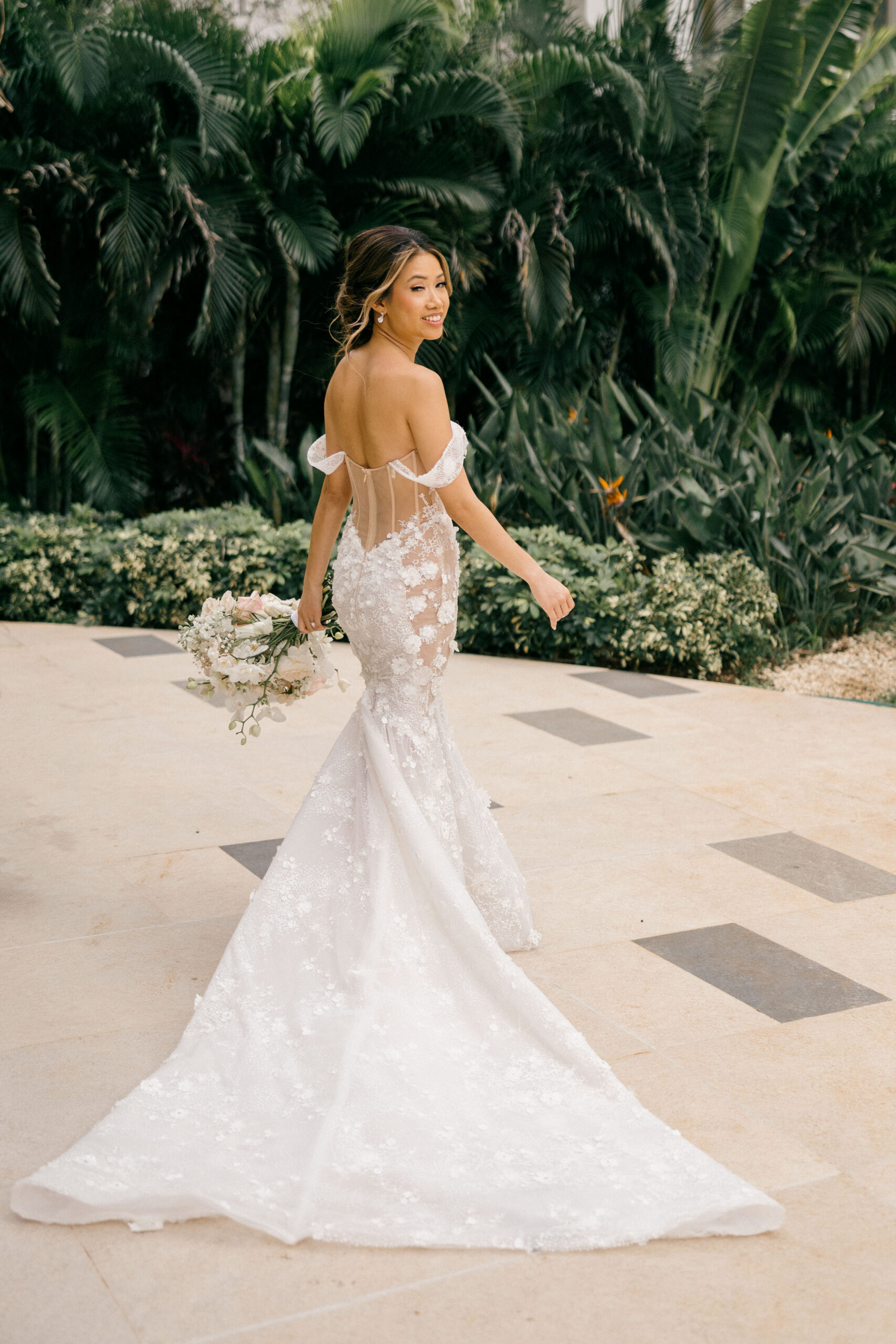 bride poses for a photo with tropical plants in the background