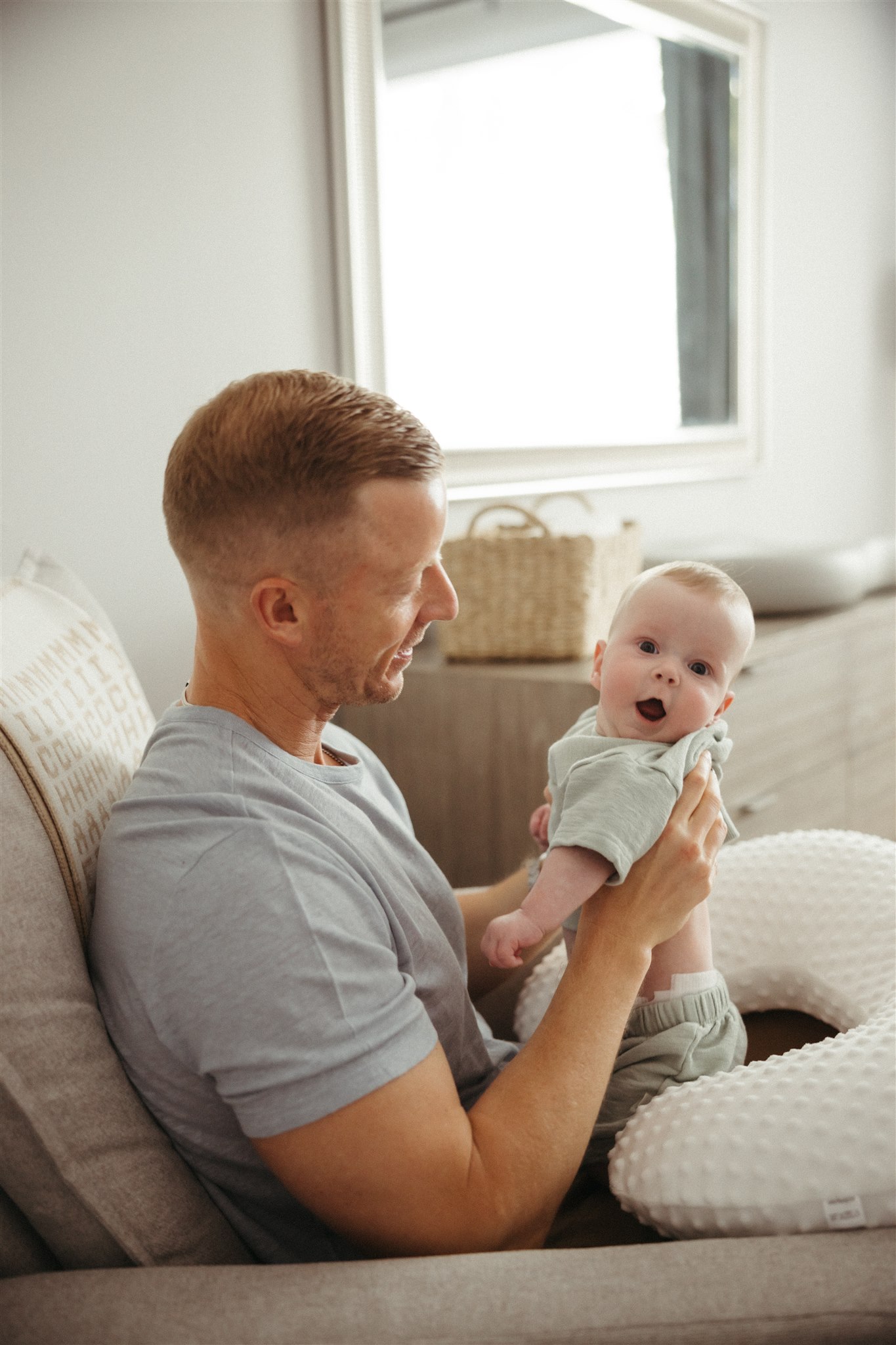 dad poses for a photo with his newborn child during their in-home newborn sessions