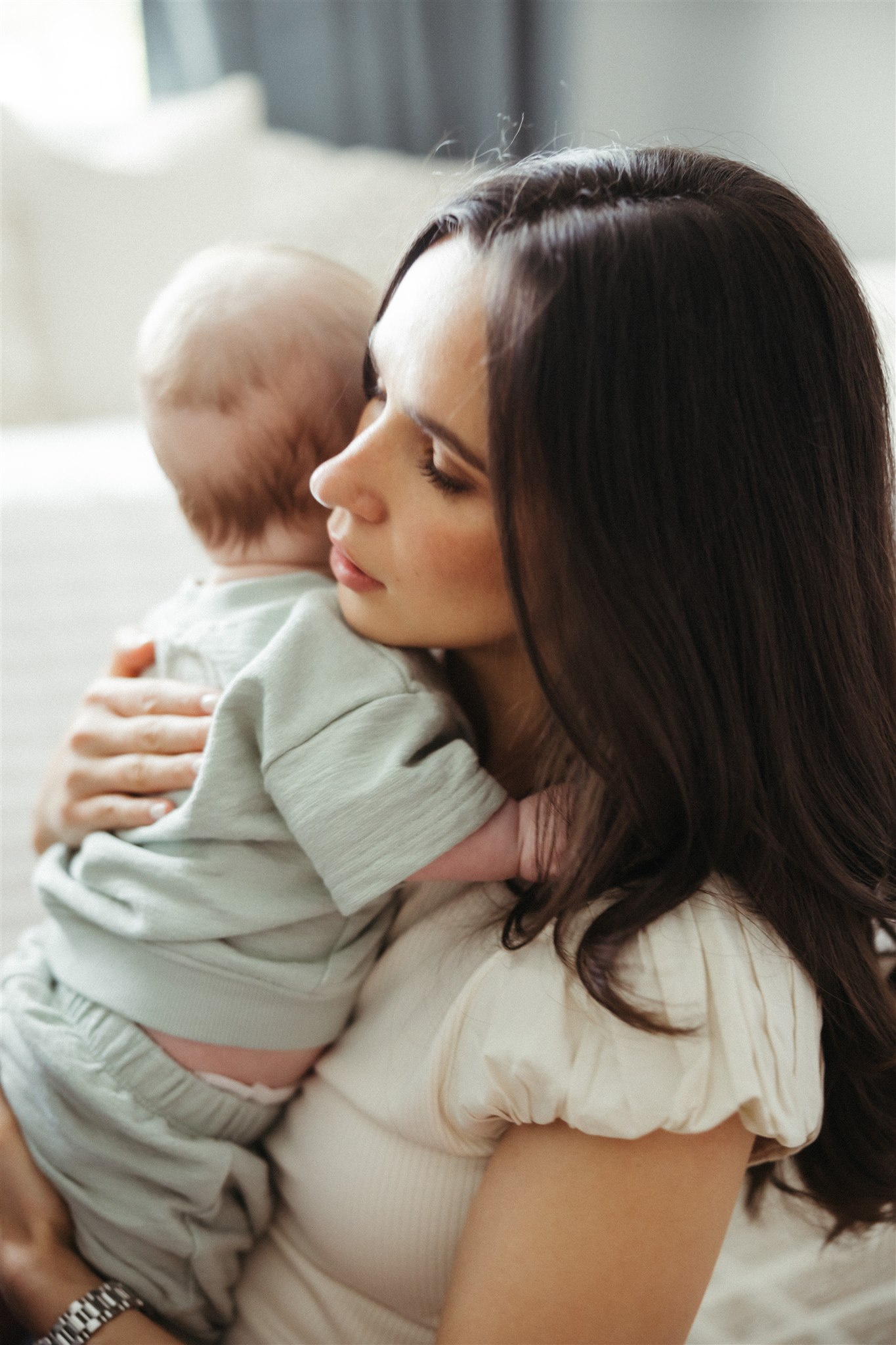 new mom poses with her newborn during their in home family photo session