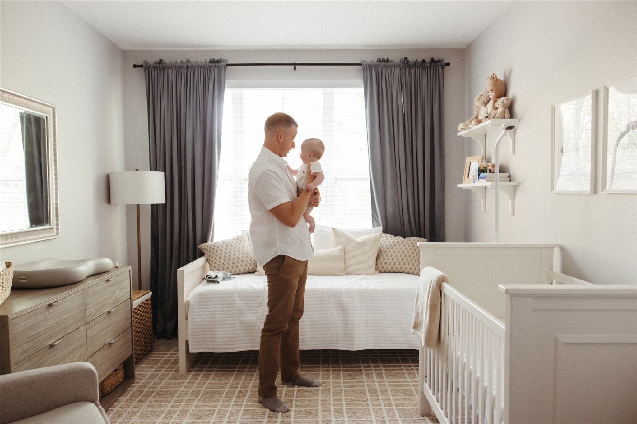 dad poses for a photo with his newborn child during their in-home newborn sessions