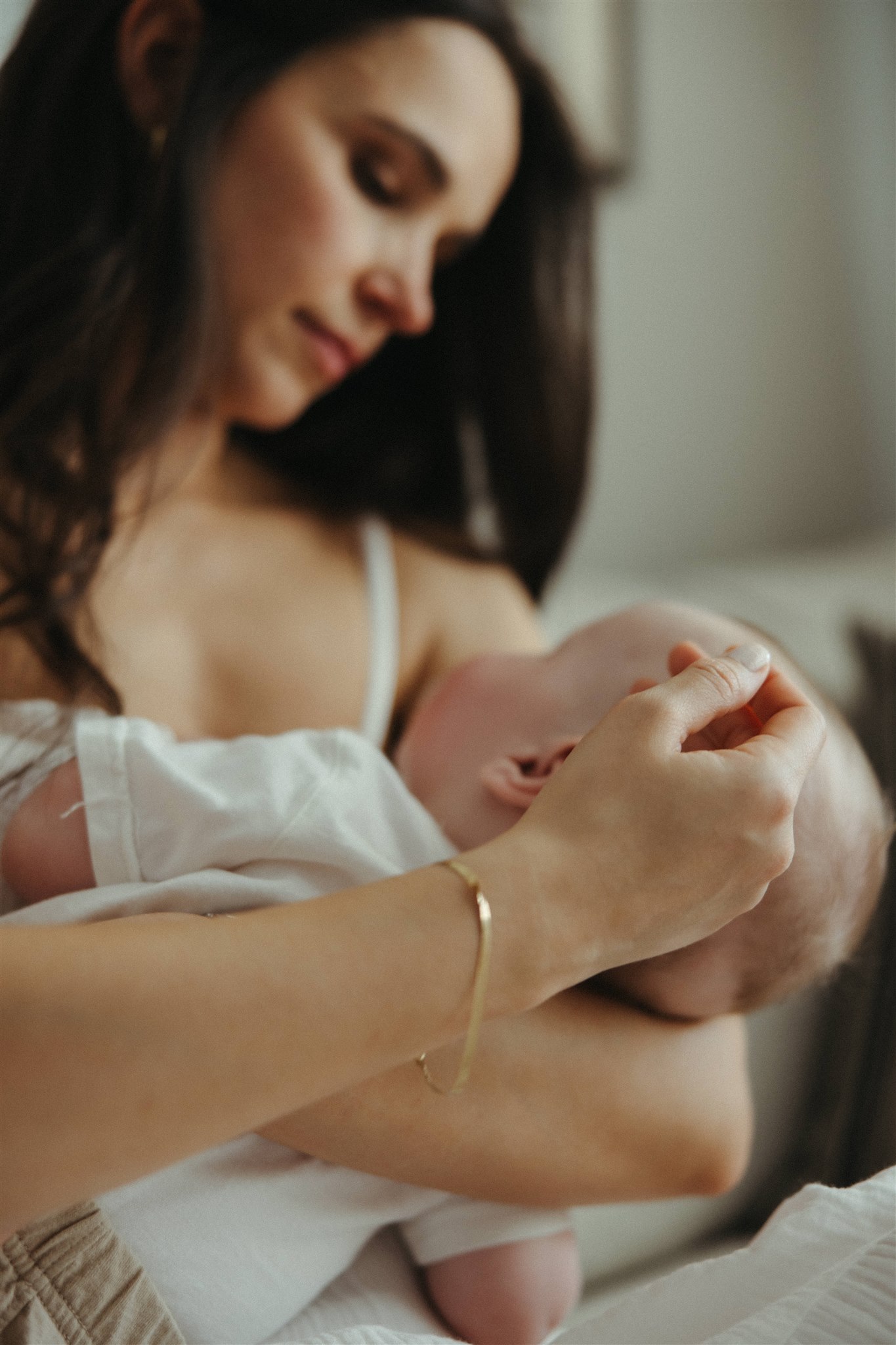 new mom poses with her newborn during their in home family photo session